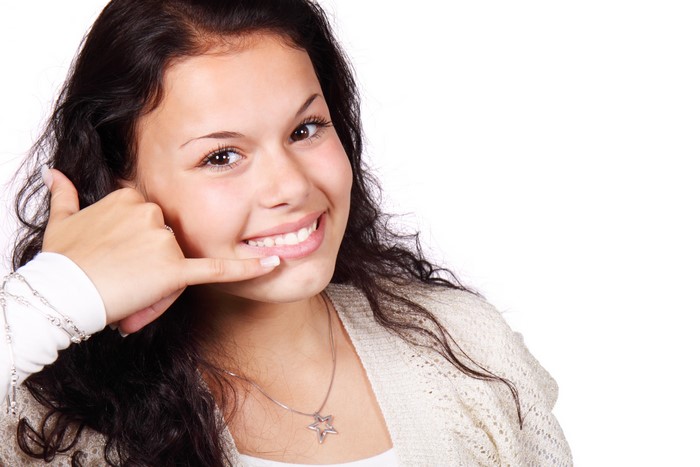 Brunette girl making call me gesture and smiling