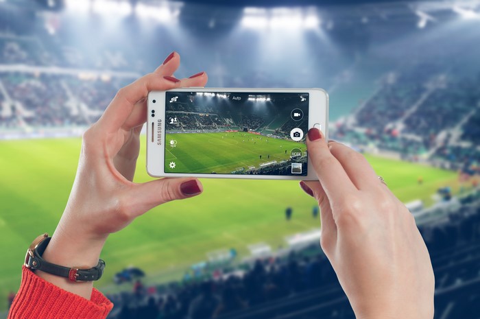 Hands holding Samsung smartphone at football stadium