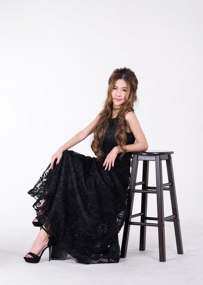 Asian woman in black dress sitting on stool