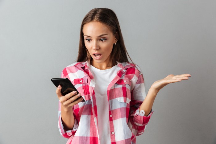 Woman with surprise emotion holding a smartphone