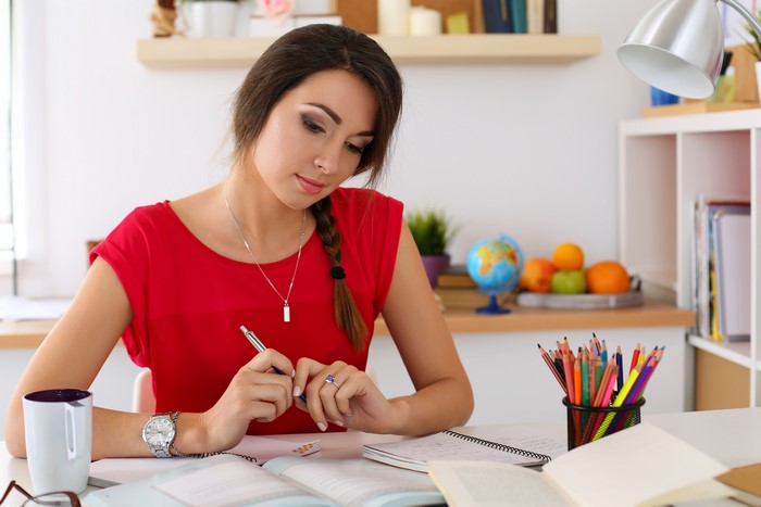 Female student studying at a desk with books and pencils