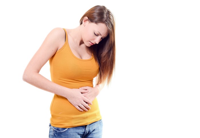 Brown haired woman holding her belly on white background