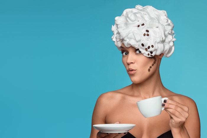 Woman with whipped cream and coffee beans hairstyle holding coffee cup