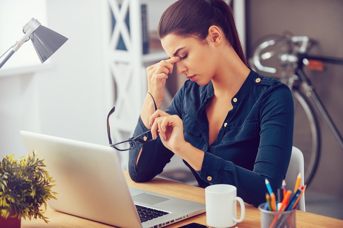Woman with fatigue at office desk with laptop