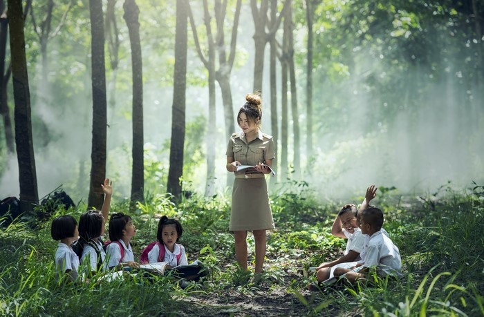 Teacher instructing children in a forest