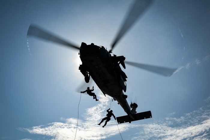 Helicopter with soldiers rappelling down