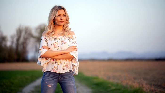 Blonde girl in jeans and blouse posing