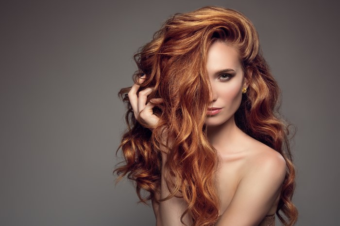 Redhead woman with wavy hair and gold earring
