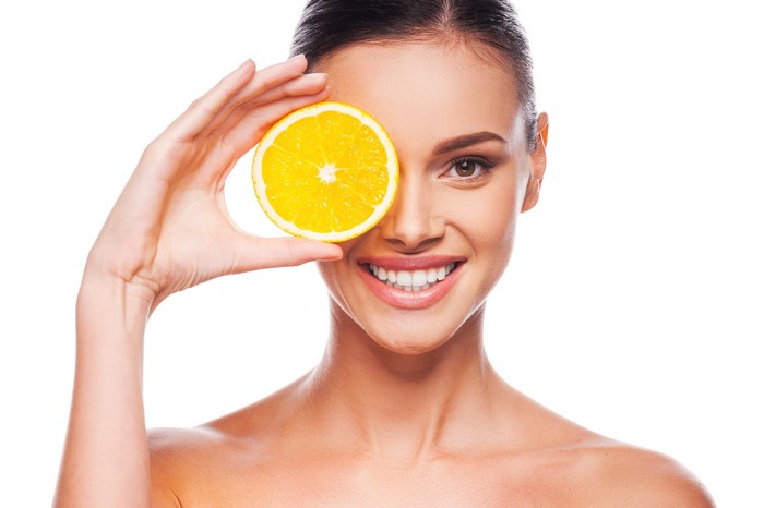 Model holding orange slice over eye