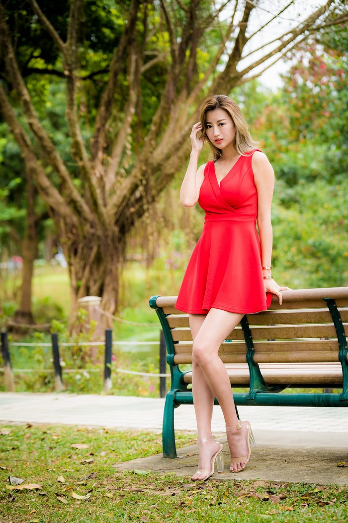 Woman in red dress sitting on park bench
