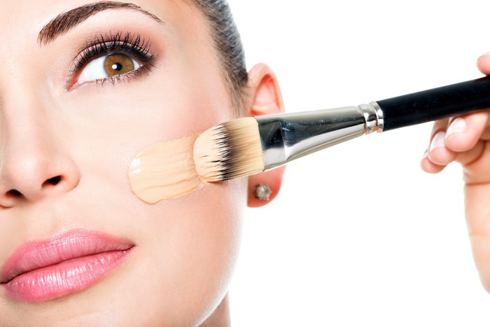 Model applying foundation with a makeup brush