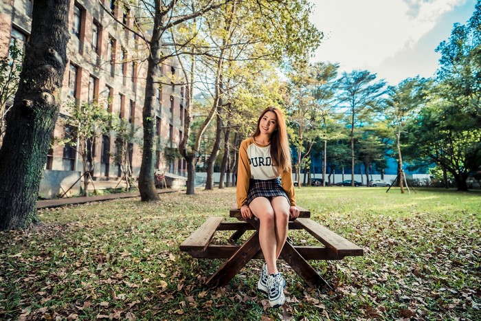 Asian woman sitting on a picnic table in a park