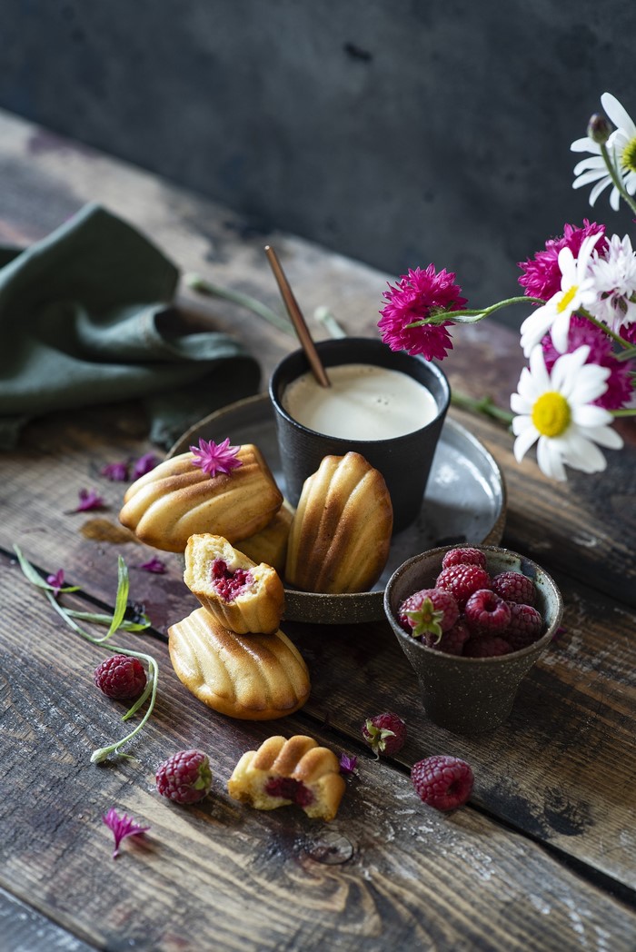 Madeleines with raspberries and coffee on a wooden table