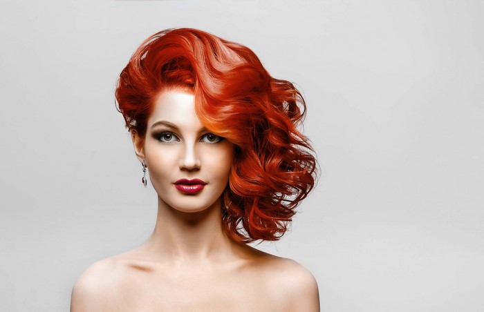 Model with red hair and makeup on gray background