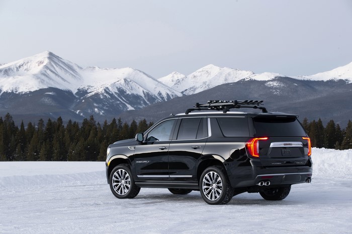 Black GMC Yukon Denali SUV with Ski Rack on Snowy Mountains