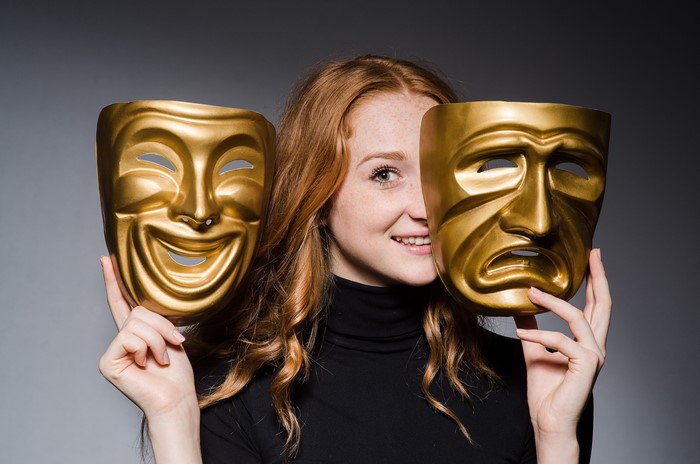 Redhead girl holding theater masks