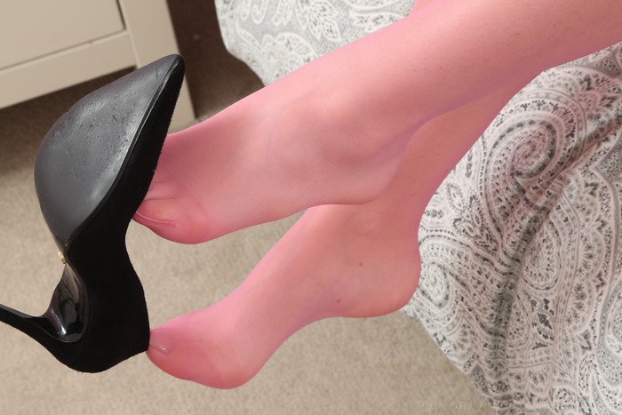 Legs in pink pantyhose with black stiletto heel
