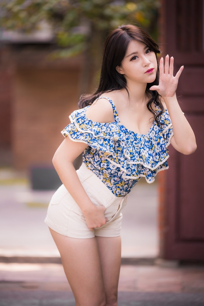 Asian woman with brown hair in a floral blouse and shorts