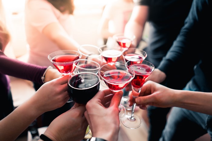 Hands toasting with red wine glasses