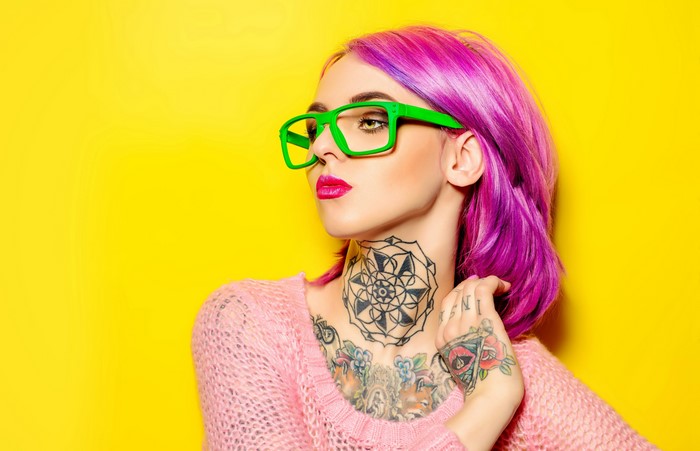 Woman with pink hair and tattoos wearing glasses