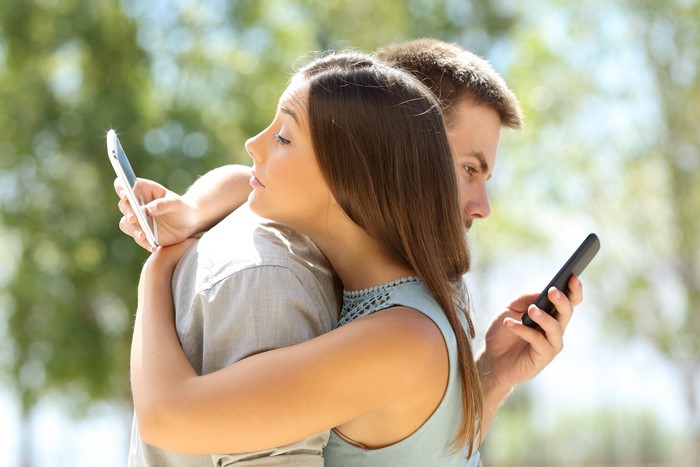 Couple Hugging and Using Smartphones