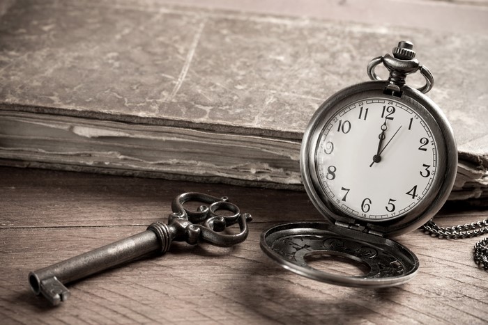 Antique pocket watch and key on a wooden table