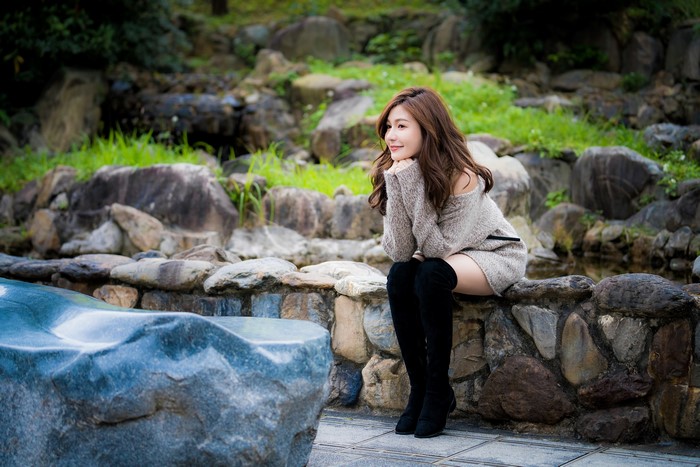 Asian woman sitting on stones wearing boots