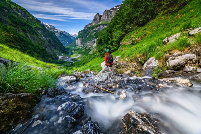 Hiker in a Mountain Valley with a Stream