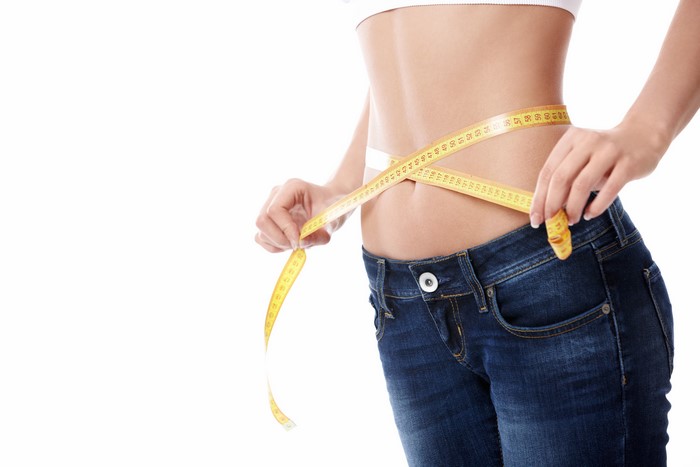 Woman measuring her waist with a tape measure