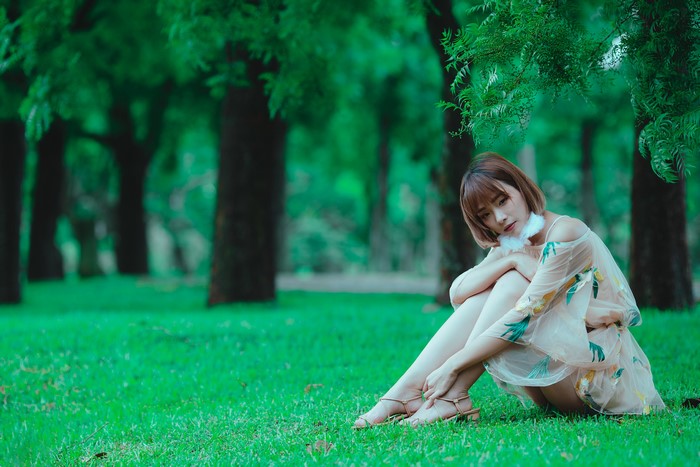 Asian woman sitting on grass in a park