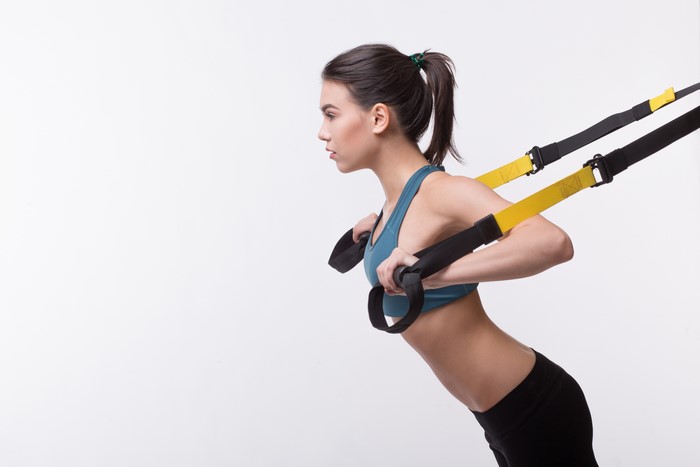 Brunette girl exercising with fitness straps