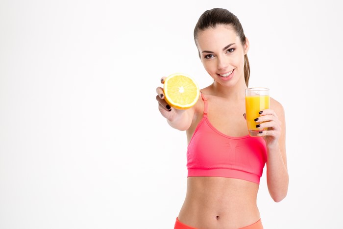 Woman holding orange slice and orange juice