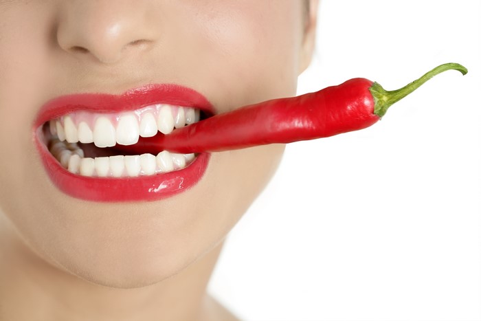 Woman biting a red chili pepper