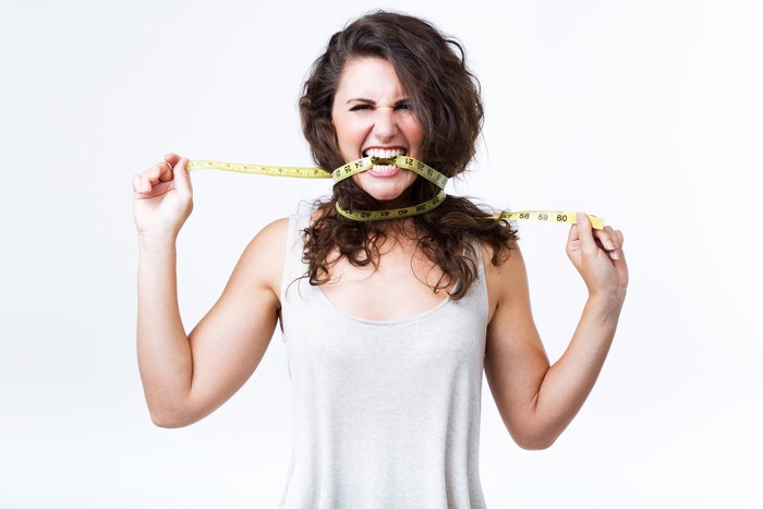 Woman biting a tape measure