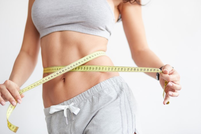 Woman measuring her waist with a tape measure