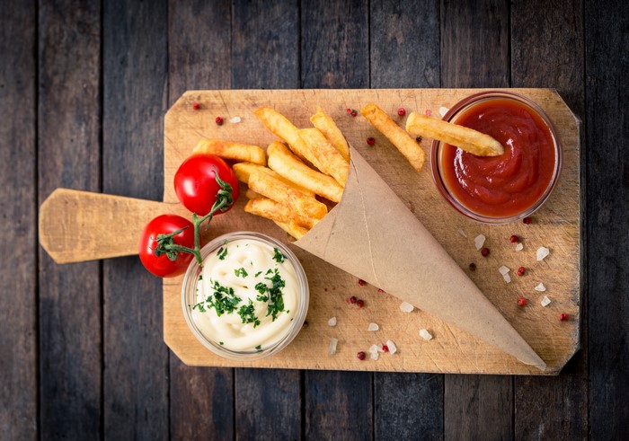 French fries with ketchup and mayonnaise on a cutting board