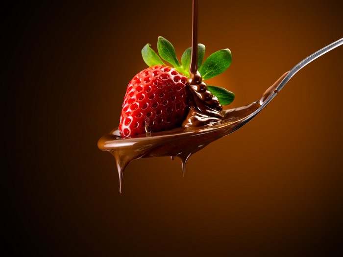Strawberry covered in chocolate on a spoon
