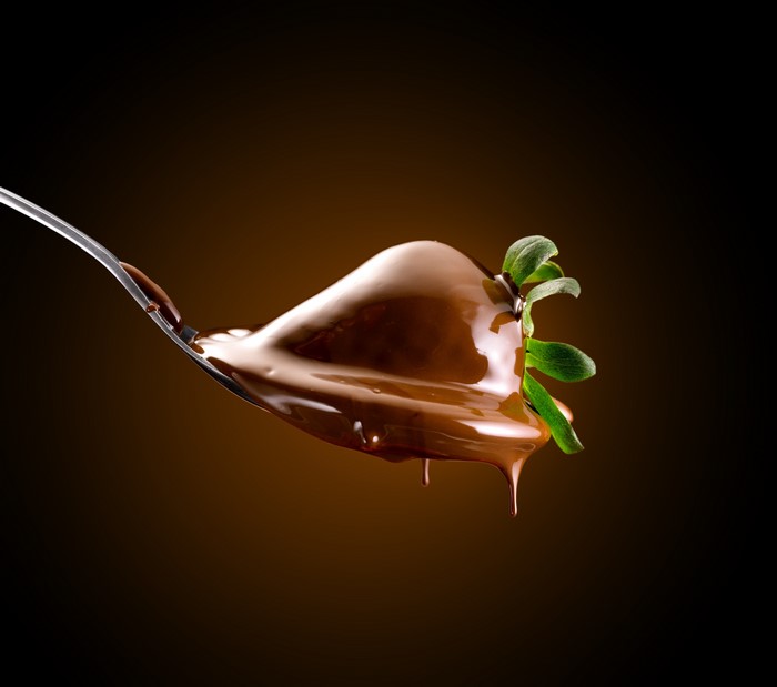 Strawberry covered in chocolate on a spoon