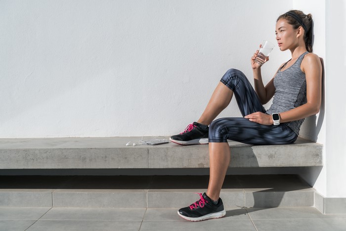 Woman in Fitness Attire Drinking Water While Resting