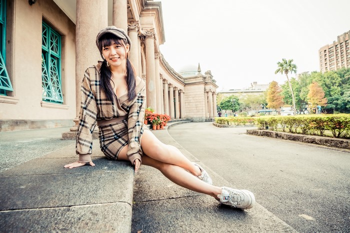 Asian woman in plaid dress and cap sitting