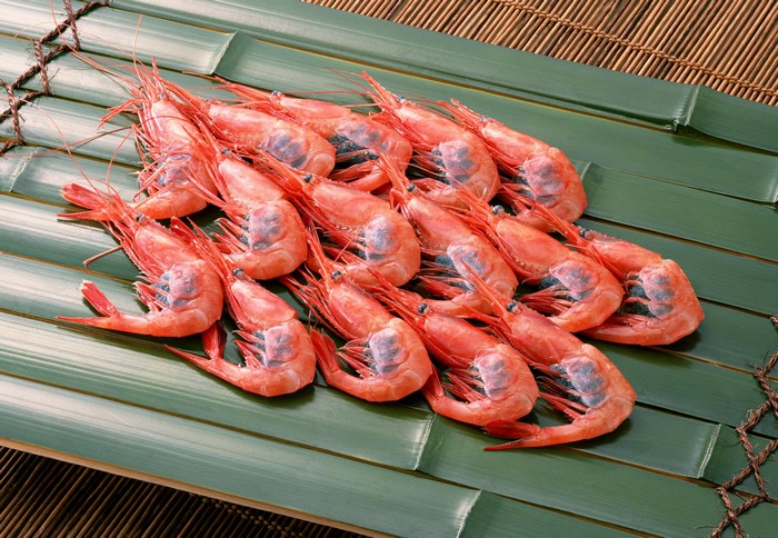 Many raw pink shrimp on bamboo mat