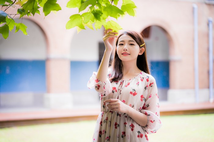 Asian woman in floral dress under branches