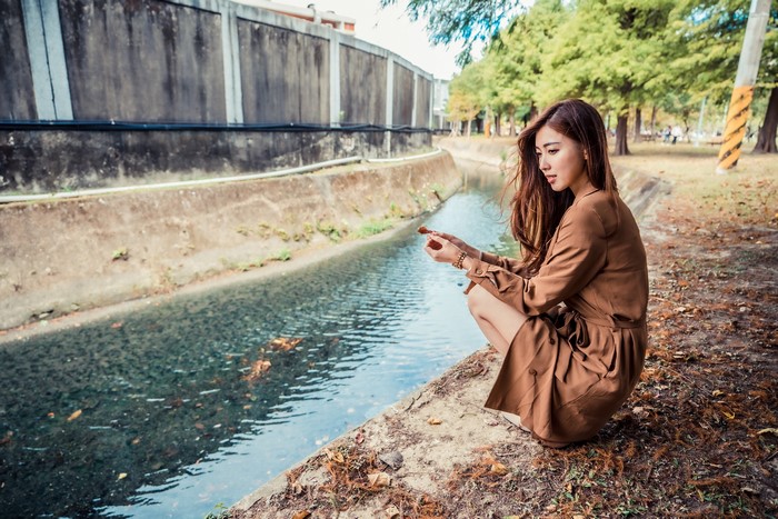 Asian woman in brown dress by canal