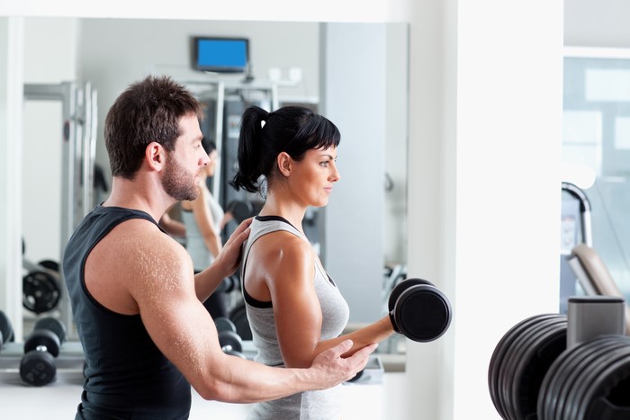 Man training woman with dumbbells in gym