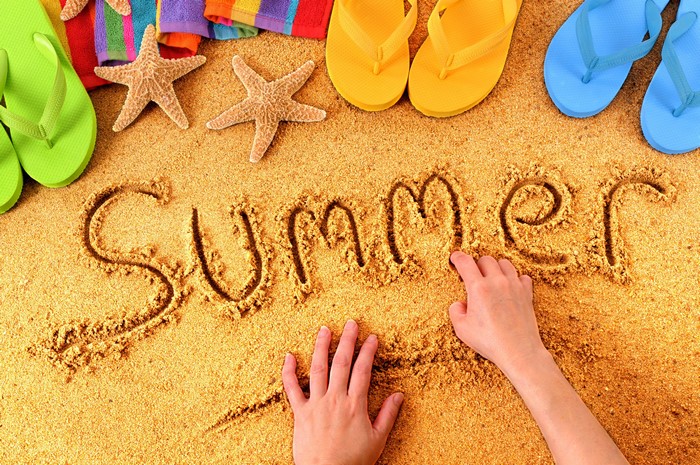 Summer written in sand with flip-flops and starfish