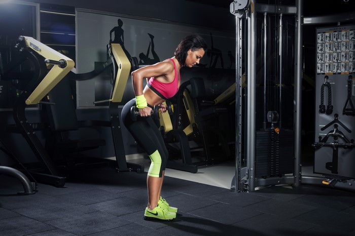 Woman performing dumbbell rows in a gym
