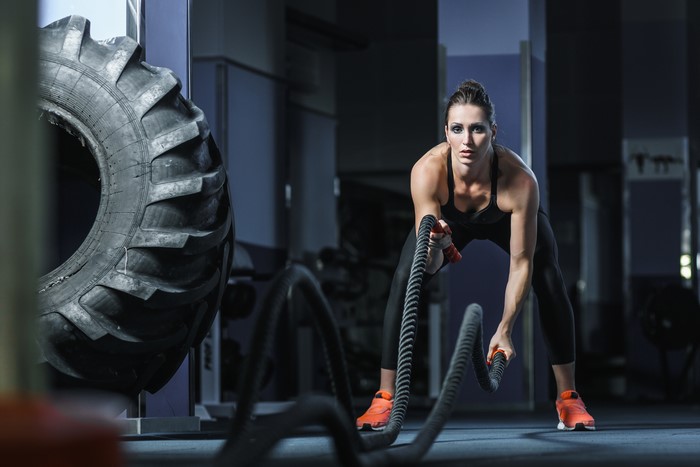 Woman working out with battle ropes in gym