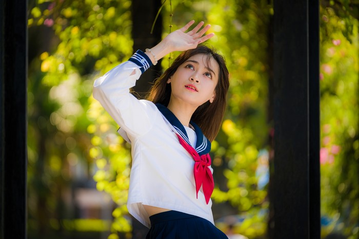 Asian schoolgirl in sailor uniform posing outdoors
