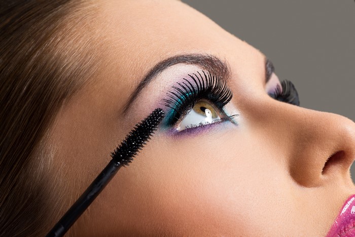 Woman applying mascara to eyelashes