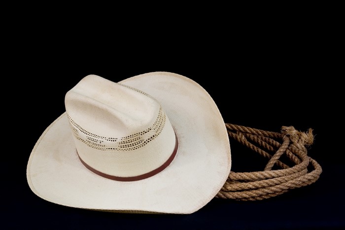 Cowboy hat and rope on black background